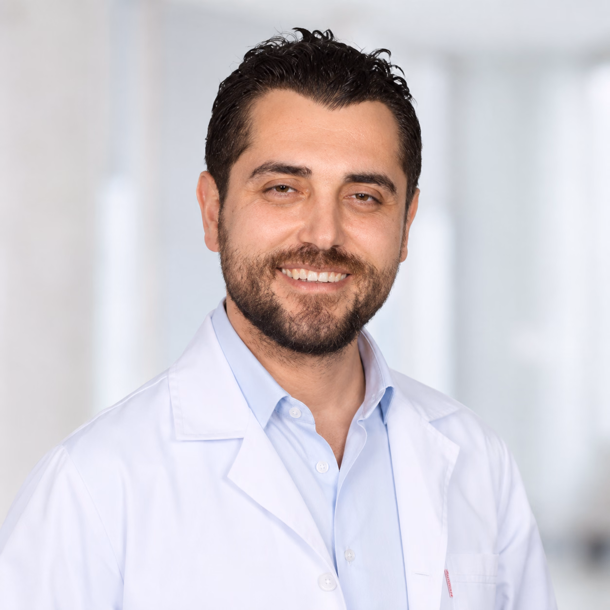 Beyaz hekim önlüğüyle Op. Dr. Cem Özlük portresi